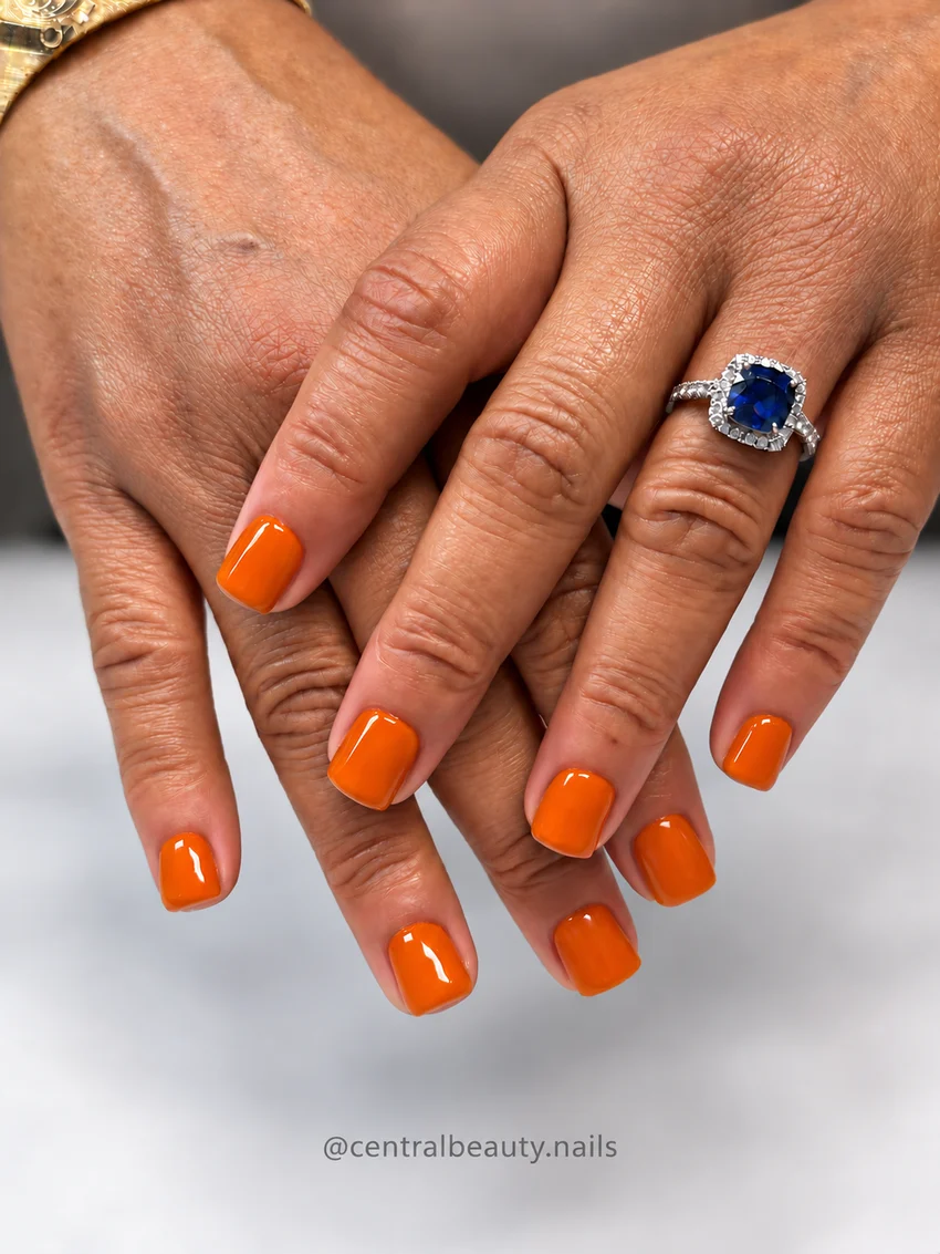 Glossy bright orange manicure on short square nails